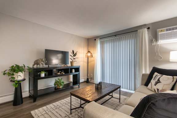A living room with a television, a couch, a coffee table, and a plant in a 1 bedroom, 1 bath 560 square foot apartment at Aspen Village Apartments in the Westwood neighborhood of Cincinnati, OH.
