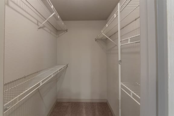 This is a photo of the primary bedroom walk-in closet in the 1486 square foot 3 bedroom, 3 bath floor plan at The Brownstones Townhome Apartments in Dallas, TX.