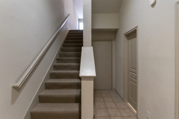 This is a photo of the stairs to the second floor and the door to the two car garage in the 1486 square foot 3 bedroom, 3 bath floor plan at The Brownstones Townhome Apartments in Dallas, TX.