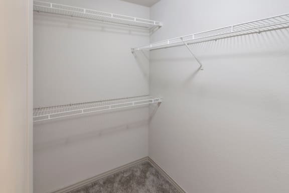 This is a photo of the first floor bedroom walk-in closet in the 1661 square foot 3 bedroom, 3 and a half bath floor plan at The Brownstones Townhome Apartments in Dallas, TX.