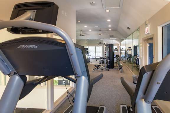 The 24-hour fitness center with treadmills, elliptical machines, and free weights at The Brownstones Townhome Apartments in the Far North Dallas neighborhood of Dallas, TX..
