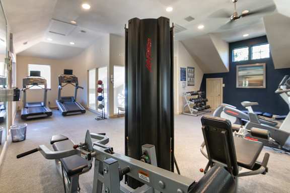 The 24-hour fitness center with treadmills, elliptical machines, and free weights at The Brownstones Townhome Apartments in the Far North Dallas neighborhood of Dallas, TX..