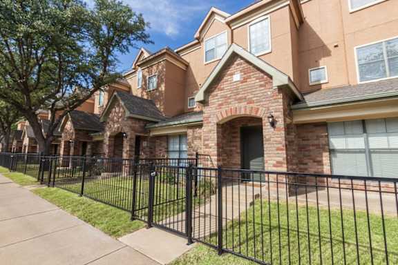 This is a photo of the townhome exteriors with a gated front yard at The Brownstones Townhome Apartments in Dallas, TX.