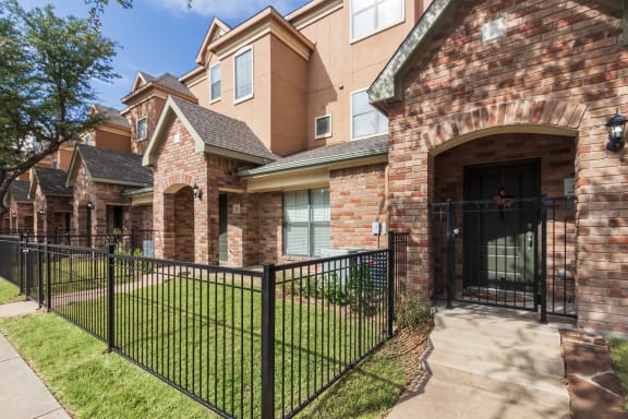 This is a photo of the townhome exteriors with a gated front yard at The Brownstones Townhome Apartments in Dallas, TX.