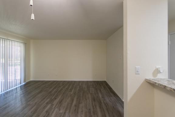 A room with wooden flooring and a window with blinds.