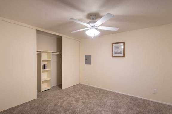 A bedroom with whtie ceiling fan and built-in shelving in the closet in a 1 bedroom, 1 bath B, 629 sq ft apartment home at The Biltmore Apartments located in the Vickery Midtown neighborhood of Dallas, TX.