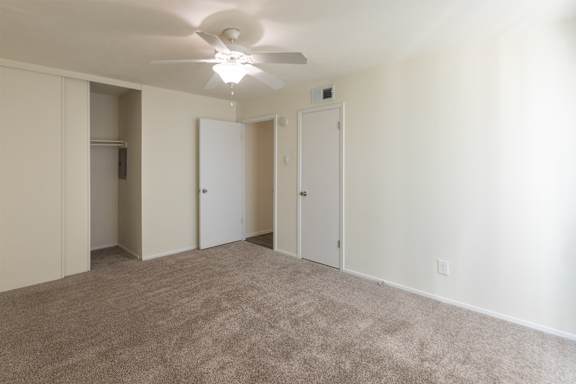Primary bedroom with view of both of its closets in a 2 bedroom, 1.5 bath 1084 sq ft, 2-floor townhome at The Biltmore Apartments located in the Vickery Midtown neighborhood of Dallas, TX.