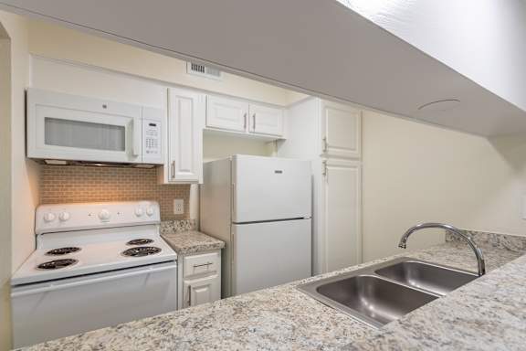 Kitchen with white cabinets and white appliances in a 2 bedroom, 1.5 bath 846 sq ft apartment home at The Biltmore Apartments located in the Vickery Midtown neighborhood of Dallas, TX.
