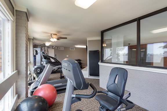 The fitness center with rowing machine, elliptical, treadmill, bike, weight system, yoga matts and free weights at Cambridge Court Apartments in Lake Highlands, Dallas, TX.