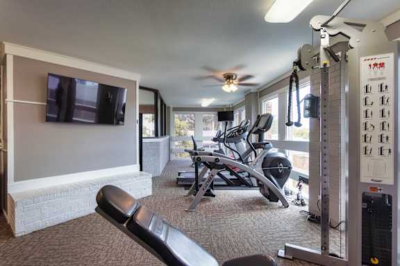 The fitness center with rowing machine, elliptical, treadmill, bike, weight system and free weights at Cambridge Court Apartments in Lake Highlands, Dallas, TX.