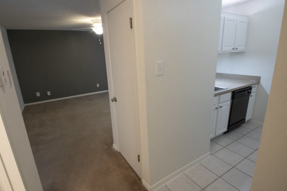 This is a photo of the coat closet, kitchen and living room of a 582 square foot 1 bedroom apartment at Cambridge Court Apartments in Dallas, TX.