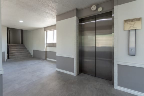 This is a photo of an elevatorin an open air hallway with new tile in the 450 square foot efficiency apartment at Cambridge Court Apartments in Dallas, TX.