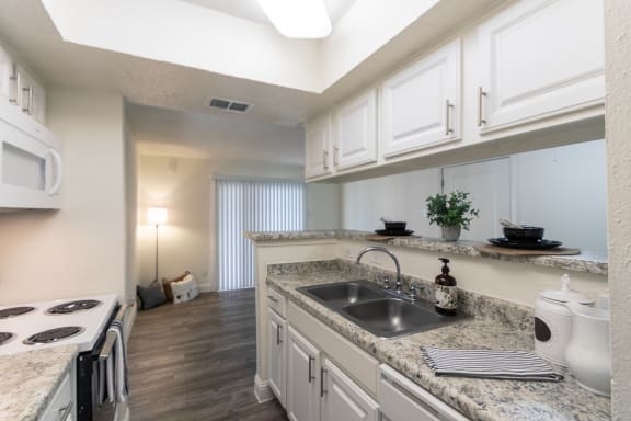 This is a photo of the living room from the kitchen of the 575 square foot 1 bedroom, 1 bath apartment at Canyon Creek Apartments in Dallas, TX