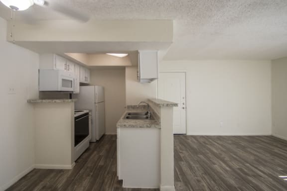 This is a photo of the living room and kitchen of the 550 square foot 1 bedroom apartment at Canyon Creek Apartments in Dallas, TX