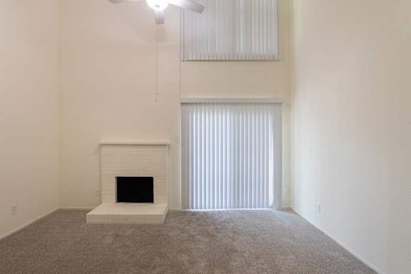 A living room with white brick fireplace and white ceiling fan in a 717 square foot 1 bedroom, 1 bath loft apartment home at Canyon Creek Apartments in Dallas Midtown neighborhood of Dallas, TX.