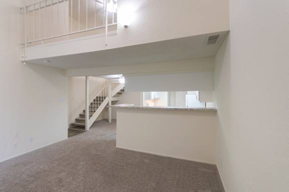 View of the kitchen, dining room and the second floor bedroom in a 717 square foot 1 bedroom, 1 bath loft apartment home at Canyon Creek Apartments in Dallas Midtown neighborhood of Dallas, TX.