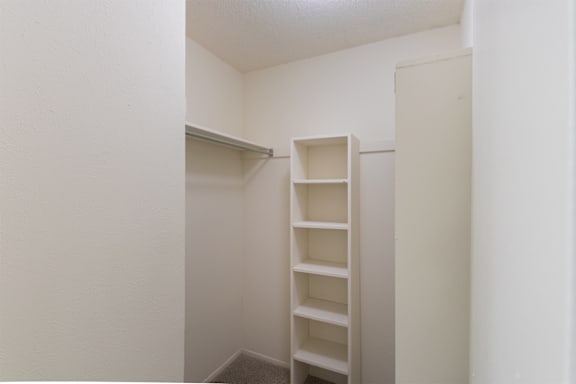 A bedroom walk-in closet with built-in shelving in a 717 square foot 1 bedroom, 1 bath loft apartment home at Canyon Creek Apartments in Dallas Midtown neighborhood of Dallas, TX.