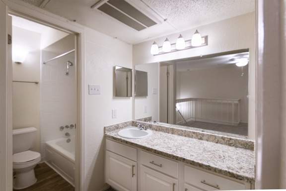A bathroom with a large white vanity in the bedroom in a 717 square foot 1 bedroom, 1 bath loft apartment home at Canyon Creek Apartments in Dallas Midtown neighborhood of Dallas, TX.