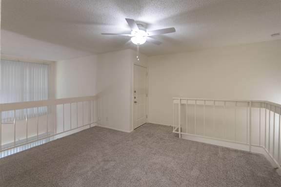 A bedroom with white ceiling fan and a view of the second floor entry door in a 717 square foot 1 bedroom, 1 bath loft apartment home at Canyon Creek Apartments in Dallas Midtown neighborhood of Dallas, TX.