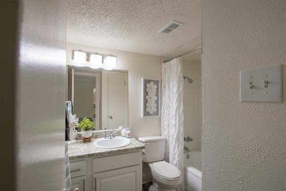 A bathroom with a white vanity in a 515 square foot 1 bedroom, 1 bath apartment home at Canyon Creek Apartments in Dallas Midtown neighborhood of Dallas, TX.