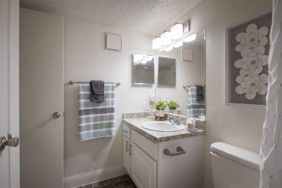 A bathroom with a white vanity in a 515 square foot 1 bedroom, 1 bath apartment home at Canyon Creek Apartments in Dallas Midtown neighborhood of Dallas, TX.