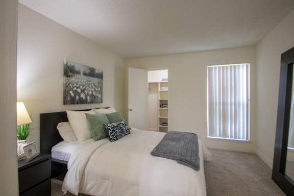 A bedroom with a large painting and a large mirror leaning against the wall in a 515 square foot 1 bedroom, 1 bath apartment home at Canyon Creek Apartments in Dallas Midtown neighborhood of Dallas, TX.