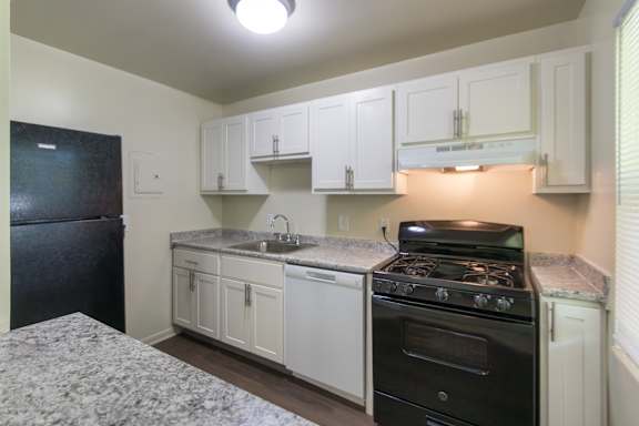 Bright kitchen with white cabinets and black appliances in a two-bedroom, two-bath apartment home