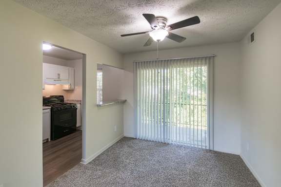 Open living and dining area with ceiling fan and sliding glass door in an 880-square-foot apartment home