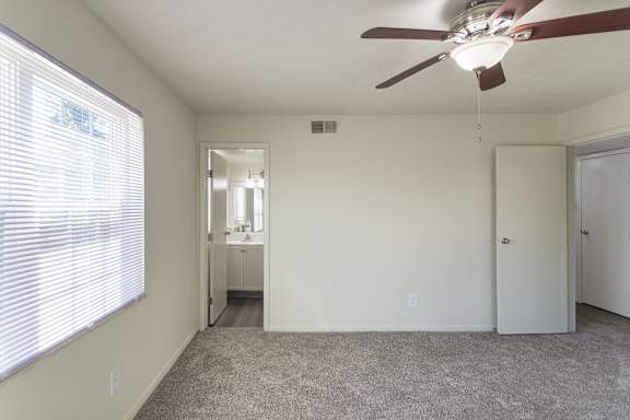 Primary bedroom with double-door closet and two windows in an 880-square-foot apartment home