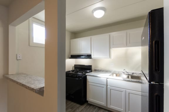 an empty kitchen with white cabinets and a black stove and refrigerator
