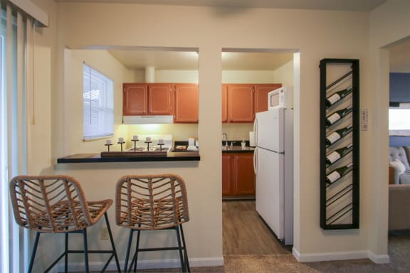 This is a photo of the kitchen with pass through breakfast bar of the 550 square foot 1 bedroom, 1 bath, balcony floor plan model apartment at College Woods Apartments in Cincinnati, OH.