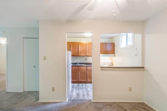 an empty living room with a kitchen in the background
