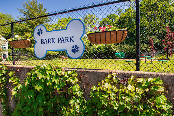 A sign that says Bark Park is hanging on a fence.