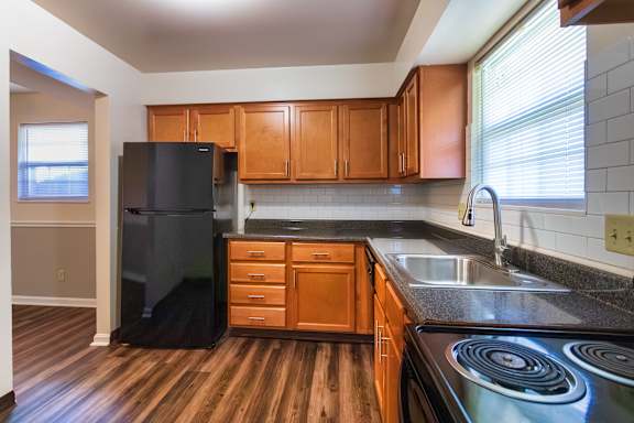A kitchen with wooden cabinets and black appliances in the 1460 square foot, 3 bedroom, 2 and a half bath townhome at Fairfield Pointe Apartments in Fairfield, OH.