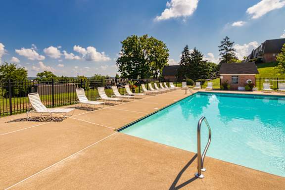 A pool surrounded by white lounge chairs at Fairfield Pointe Apartments in Fairfield, Ohio.