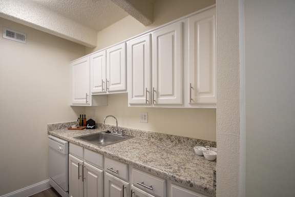 A kitchen with white cabinets Dining in a 1 bedroom, 1 bath apartment home at Harvard Square Apartments in the Vickery Midtown neighborhood of Dallas, TX.