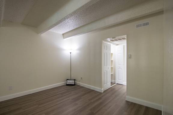 A living room with hardwoodlike flooring in a 1 bedroom, 1 bath apartment home at Harvard Square Apartments in the Vickery Midtown neighborhood of Dallas, TX.