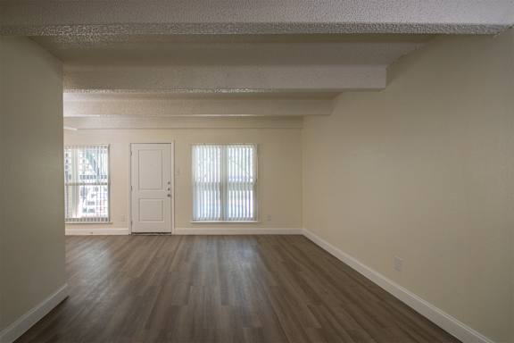 Living room with hardwoodlike flooring in a 1 bedroom, 1 bath apartment home at Harvard Square Apartments in the Vickery Midtown neighborhood of Dallas, TX.