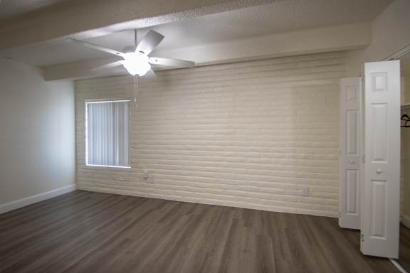 A bedroom with white ceiling fan and hardwoodlike flooring in a 1 bedroom, 1 bath apartment home at Harvard Square Apartments in the Vickery Midtown neighborhood of Dallas, TX.
