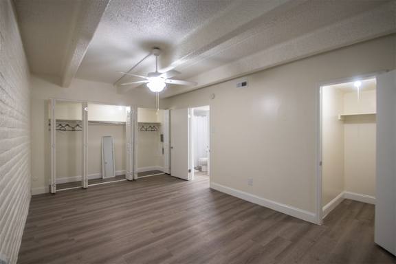 A bedroom with white ceiling fan and hardwoodlike flooring in a 1 bedroom, 1 bath apartment home at Harvard Square Apartments in the Vickery Midtown neighborhood of Dallas, TX.