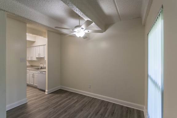 A dining room with a ceiling fan and a window with blinds in a 2 bedroom, 1 bath apartment home at Harvard Square Apartments in the Vickery Midtown neighborhood of Dallas, TX.