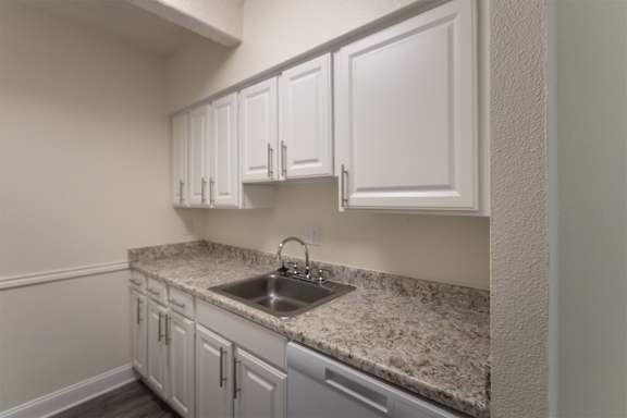 A kitchen with white cabinets in a 2 bedroom, 1 bath apartment home at Harvard Square Apartments in the Vickery Midtown neighborhood of Dallas, TX.