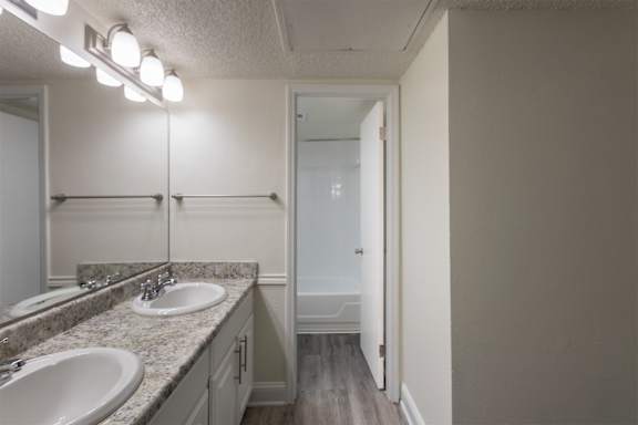 A bathroom with two sinks and a white vanity in a 2 bedroom, 1 bath apartment home at Harvard Square Apartments in the Vickery Midtown neighborhood of Dallas, TX.