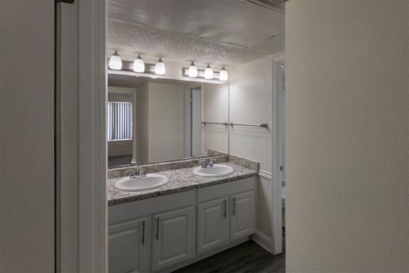 A bathroom with a white vanity in a 2 bedroom, 1 bath apartment home at Harvard Square Apartments in the Vickery Midtown neighborhood of Dallas, TX.