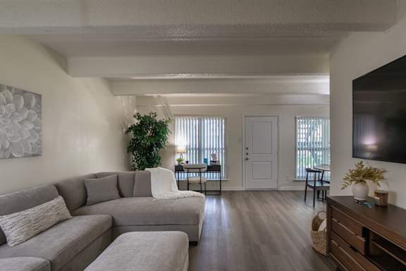 Open living room with sectional seating and patio access at Harvard Square Apartments in Dallas