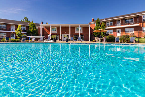 Community pool with clear blue water and surrounding apartment homes at Lake of the Woods Apartments
