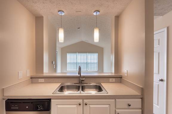 Breakfast bar and kitchen sink in the Catamaran apartment at Nantucket Apartments, looking toward the living room window and pendant lighting.