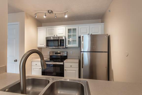 itchen in the Catamaran 1-bedroom apartment, with white cabinets, stainless-style appliances, sink, track lighting, and a view toward the living area.