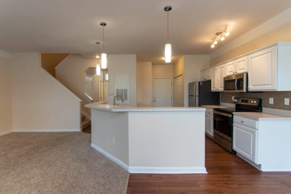 This is a photo of the kitchen and living room in the 1578 square foot, 3 bedroom, 2 and 1/2 bath Flagship floor plan at Nantucket Apartments in Loveland, OH.