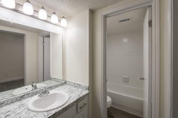 A bathroom with white vanity 1 bedroom, 1 bath apartment home at Princeton Court Apartments in the Vickery Midtown neighborhood of Dallas, TX.